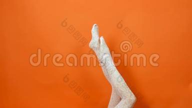 白鱼网<strong>丝袜</strong>完美的女人腿在明亮的橙色背景工作室。
